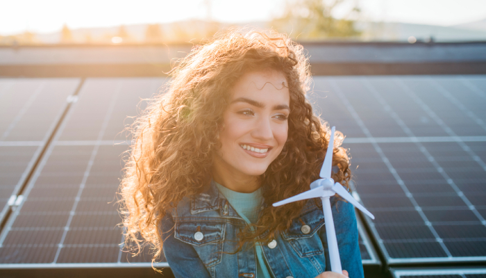 Fotografía de mujer sonriendo y detrás de ella, hay panales solares. 