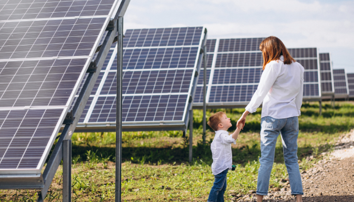 Madre e hijo caminando entre paneles solares. La madre sabe que es una buena inversión.
